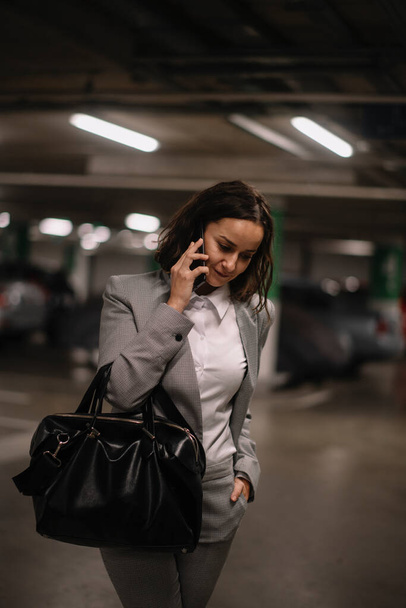 beautiful young businesswoman using phone in indoor parking - Photo, Image