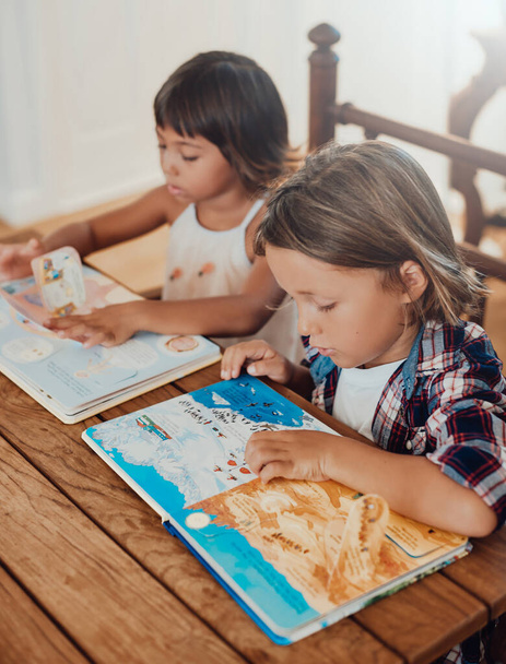 Двое детей днем читают книгу за столом в современной квартире - Фото, изображение