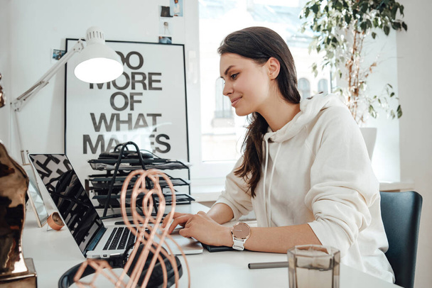 Örömteli nő dolgozik laptop ül asztalnál az irodában - Fotó, kép