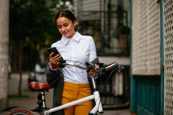 Mujer joven con bicicleta usando teléfono inteligente - Foto, imagen