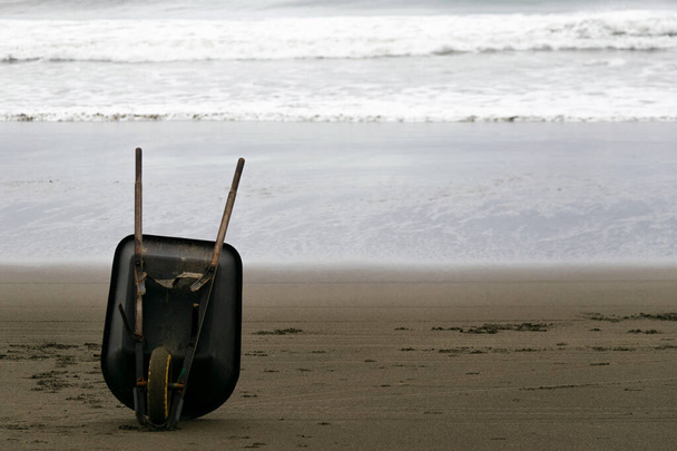 Carretilla abandonada en la playa junto al mar - Foto, imagen