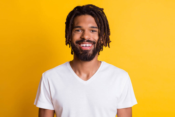 Photo of friendly dark skin guy beaming smiling wear casual t-shirt isolated yellow color background - Фото, изображение
