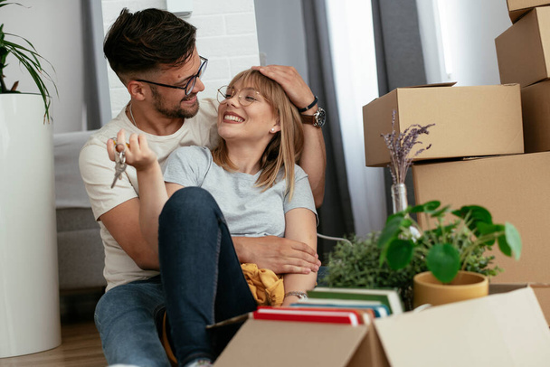Mann und Frau ziehen in die Wohnung ein. Glückliches Paar packt seine Habseligkeiten aus - Foto, Bild