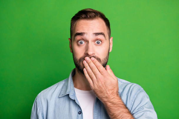 Portrait of scared guy hand lips wear blue shirt isolated on vibrant green color background - Fotografie, Obrázek