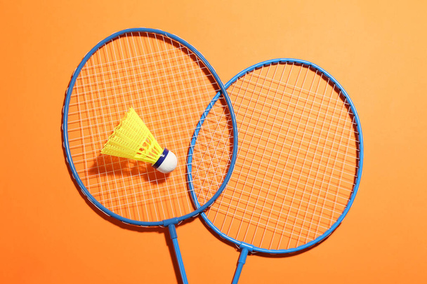 Badminton rackets and shuttlecock on orange background, flat lay. Space for text - Fotó, kép