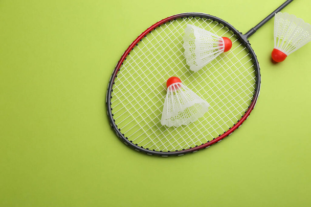 Badminton racket and shuttlecocks on light green background, flat lay. Space for text - Fotó, kép