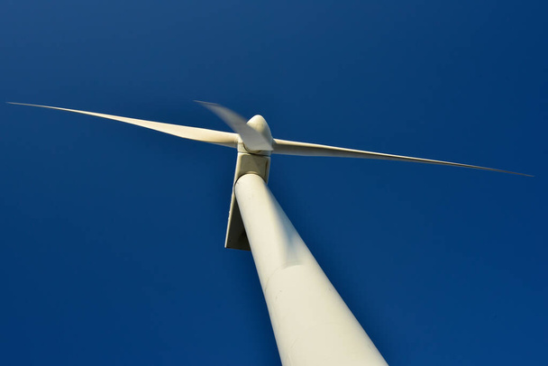 Detailní záběr větrného generátoru věže, který vyčnívá na pozadí modré oblohy. Turbína, která šetří životní prostředí a vyrábí zelenou energii. - Fotografie, Obrázek