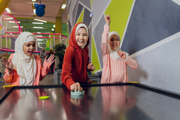 children in muslim clothes play air hockey. - Foto, imagen