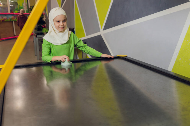 children in muslim clothes play air hockey. - Fotoğraf, Görsel