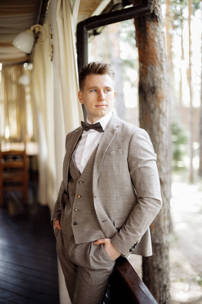 Stylish young man in a business suit.Handsome groom posing. Groom in suit posing by the window . High quality photo - Photo, Image