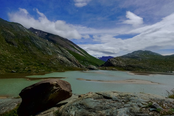 solo roca grande en un lago con islas de arena en las montañas durante el senderismo - Foto, imagen