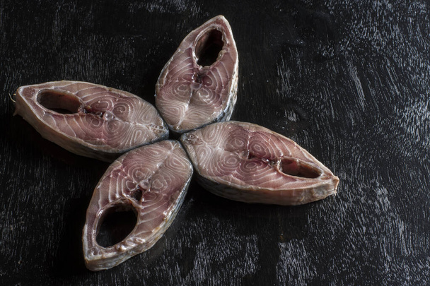 Кусочки Tenualosa Ilisha или Hilsha рыбы на черном деревянном фоне - Фото, изображение