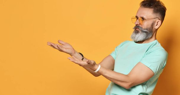 bright elderly man with a beard stretches out two hands in surprise in surprise that you are suggesting I do not understand you - Foto, Imagem