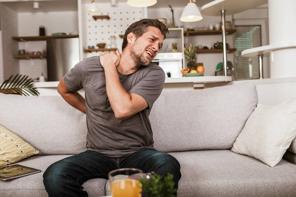 Nieszczęśliwy człowiek cierpiący na ból szyi w domu - Zdjęcie, obraz