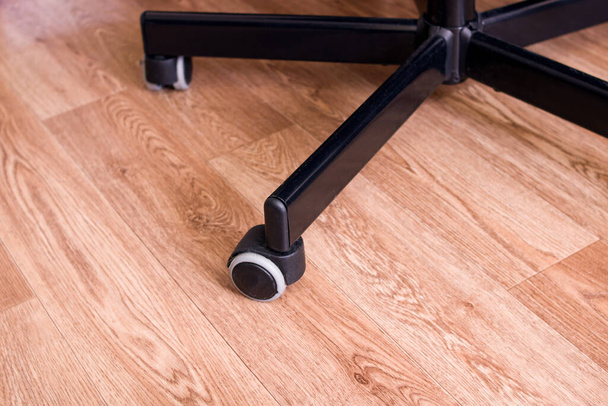 Roues de chaise de bureau sur un plancher en bois gros plan - Photo, image