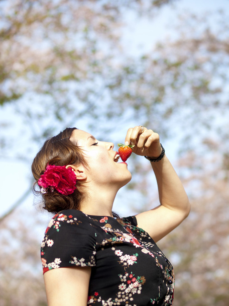 Красива дівчина їсть полуницю під час пікніка навесні
 - Фото, зображення