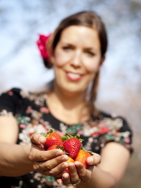 mooi meisje geeft u aardbeien tijdens een zonnige dag - Foto, afbeelding