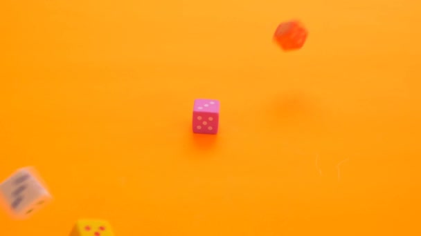 Koncepcja gier planszowych. gry losowe. Kolorowe kostki powoli spadają na pomarańczowe tło - Materiał filmowy, wideo