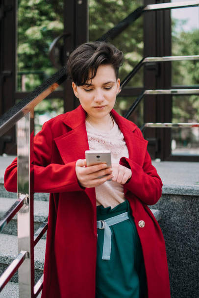 Gen z, social media, influencer, technology, youth millennial people concept. Young brunette girl with short hair using mobile phone outdoor - Photo, Image