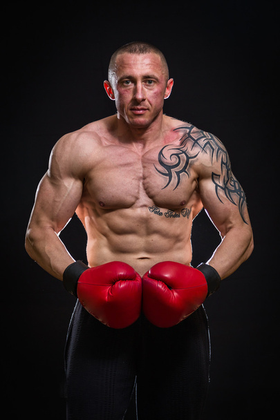 Man in tattoo posing with boxing gloves - Fotó, kép