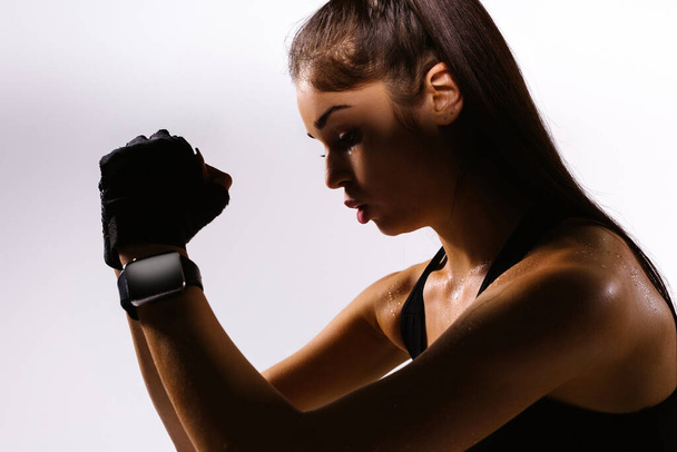 Enlarged profile dark photo of fitness woman exercising, looking down, on gray background. Sweaty caucasian brunette, breathing workout - Valokuva, kuva