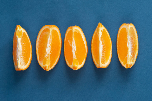 φέτες πορτοκαλιού φρούτων σε μπλε φόντο, έννοια υγιεινής διατροφής, κενό χώρο για κείμενο - Φωτογραφία, εικόνα