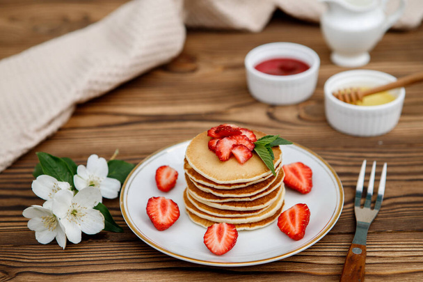 Healthy summer breakfast, homemade classic American pancakes with fresh berries and honey on a wooden background. Delicious pastries, dessert. - 写真・画像