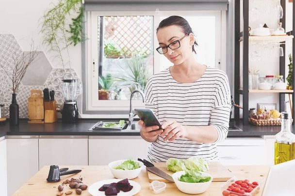 台所で野菜サラダを作る女性。健康食品。健康的なライフスタイルのコンセプト｜Vegan Salad.Cooking at Home - 写真・画像