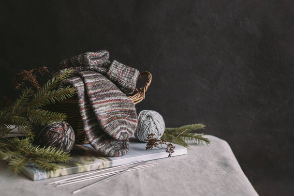 Ein Paar handgestrickte Socken mit Wollknäueln und Stricknadeln. Natürliche Farben. Dunkler rustikaler Hintergrund. Platz für Text. - Foto, Bild