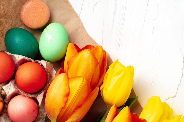 Painted Easter eggs in an eggbox with fresh tulips close up - Fotó, kép