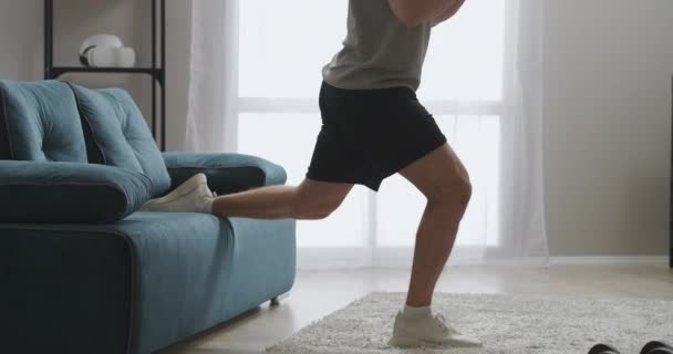 erős férfi edzés otthon, csinál guggolás az egyik lábát a nappaliban, izmos férfi test edzés közben - Felvétel, videó