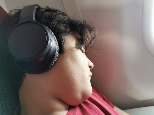 Menino relaxante ouvir música no fone de ouvido durante o voo. - Foto, Imagem