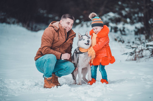 Happy father and little daughter and husky dog in winter forest walking in winter.new - Foto, afbeelding
