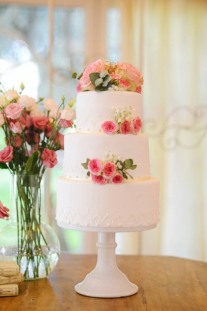 Красивий весільний торт з трьома ярусами і свіжими трояндами
 - Фото, зображення