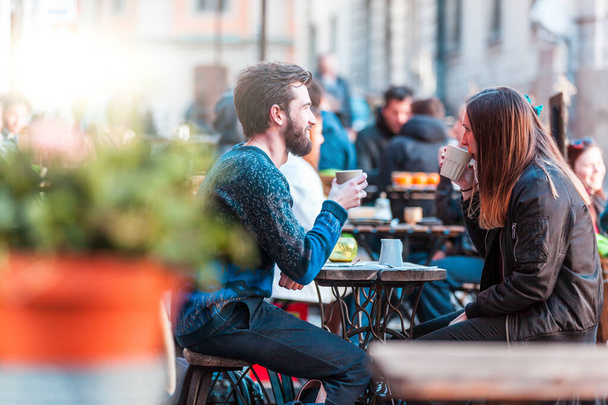 Hipster friends drinking coffee in Stockholm old town - Young couple sitting face to face outdoors and enjoying time together - Open bar with social distancing in place - Фото, зображення