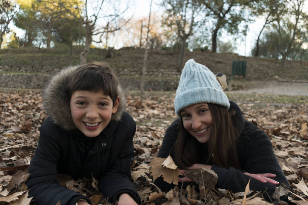 乾燥した葉の上に横たわる母と息子 - 写真・画像
