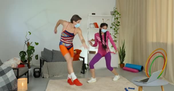 Couple actif caucasien homme et femme faisant des exercices ensemble joyeusement danser se déplacent rythmiquement avec leurs jambes porter des masques médicaux de protection contre le virus, concept de sport en lock-up - Séquence, vidéo