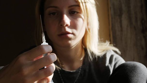 Visage déprimé d'une fille qui pense à une seringue avec de l'héroïne - Photo, image