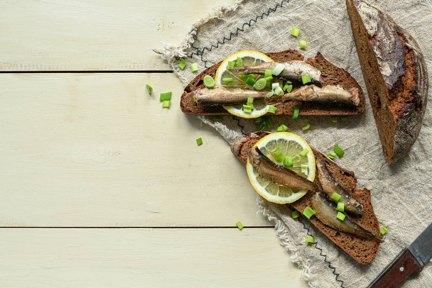 Sandwich with sprats. Sprat in oil. On a wooden background. - Foto, afbeelding