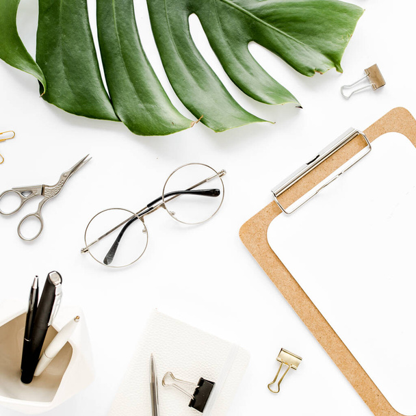 Home office workspace mockup with tropical leaves Monstera, clipboard, and accessories on white background. Flat lay, top view - Fotoğraf, Görsel