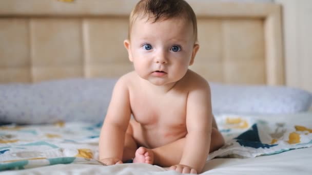 Gesundes süßes Baby sitzt ohne Kleidung auf dem Bett. - Filmmaterial, Video