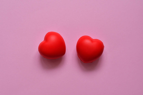 two red hearts on a pink background.Concept of support, love, care.valentines day or 14 february in quarantine.Flat lay, top view.selective focus. - Foto, immagini