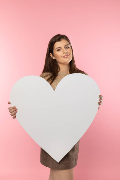 Girl with a large white heart shape in the hands. A student in love stands and holds a large heart shape in her hands. Valentines Day and love. - Fotoğraf, Görsel