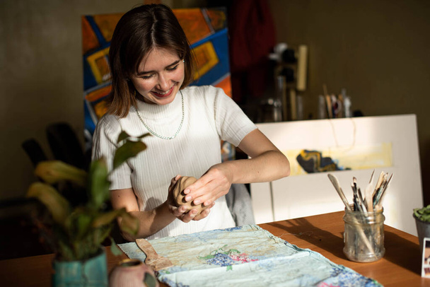 Junger Künstler formt rohe Tonerde im Kunstatelier. Mädchen formen aus Ton Skulpturen im Atelier des Künstlers. Geschäftsfrau in ihrem Töpferladen - Foto, Bild