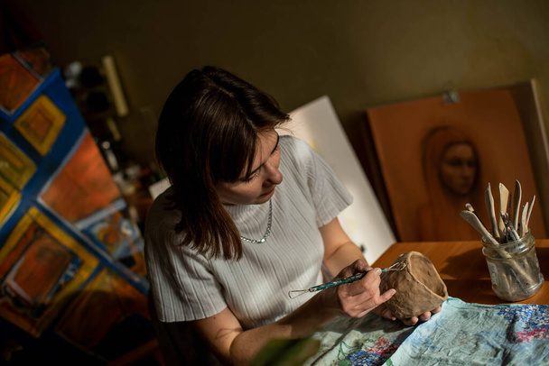 nuori taiteilija muotoilee raakaa savea taidestudiossa. Tyttö muotit savesta veistos taiteilijan studiossa. Liike nainen hänen keramiikka myymälä - Valokuva, kuva