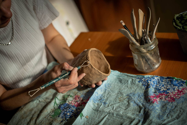 Töpferei. Ein Mädchen mit einer Schnur in der Hand schneidet die oberste Schicht von Schlehm ab. Der Prozess der Modellierung von Keramik. - Foto, Bild