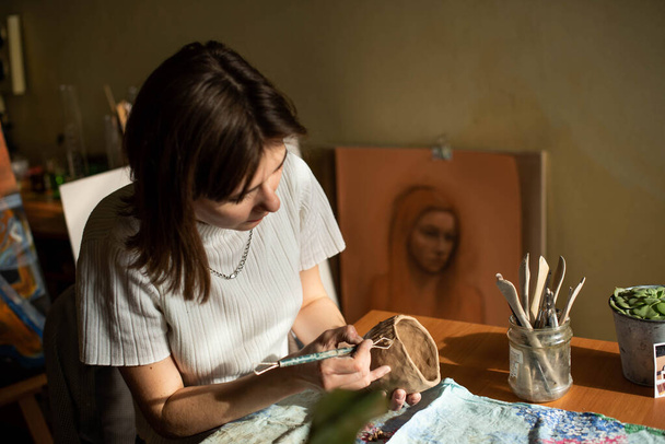 mladý umělec formující syrovou hlínu v uměleckém studiu. Dívčí plísně z hliněné plastiky v ateliéru umělce. Obchodní žena ve svém obchodě s keramikou - Fotografie, Obrázek