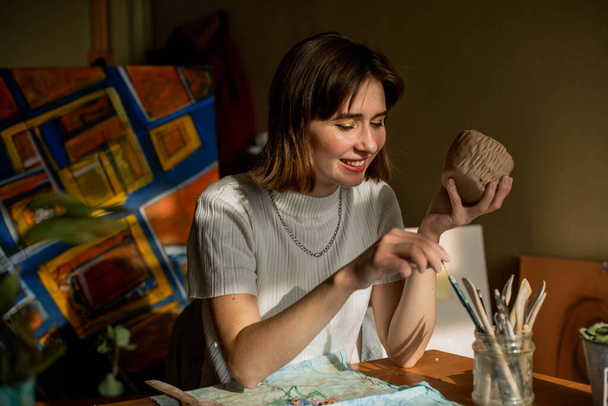 young artist moulding raw clay in art studio. Girl molds from clay sculpture in the artist's studio. Business woman at her pottery store - Foto, immagini