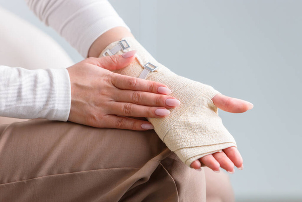 Femme touchant son poignet douloureux enveloppé avec un bandage orthopédique élastique souple de soutien après un sport infructueux ou une blessure, fermer. Syndrome du canal carpien, arthrite, entorse au bras.  - Photo, image
