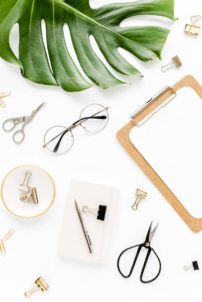 Home office workspace mockup with tropical leaves Monstera, clipboard, and accessories on white background. Flat lay, top view - Foto, imagen
